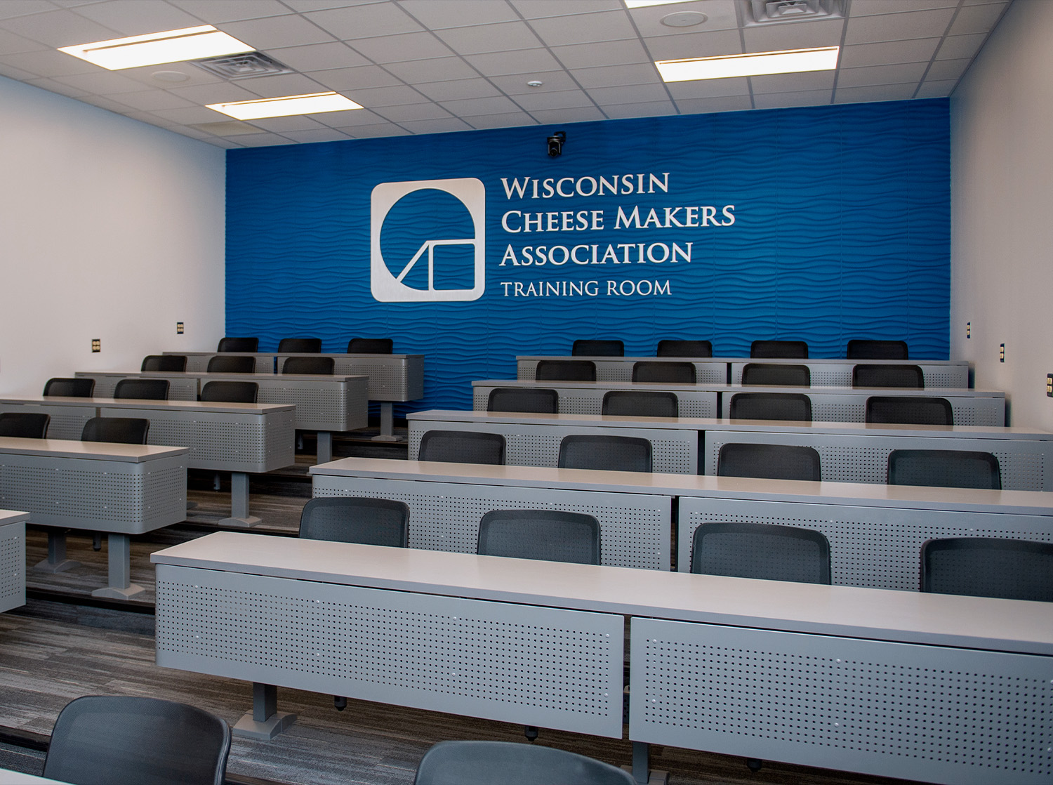 A large lecture style meeting room with "Wisconsin Cheese Makers Association" in large letters on the back wall