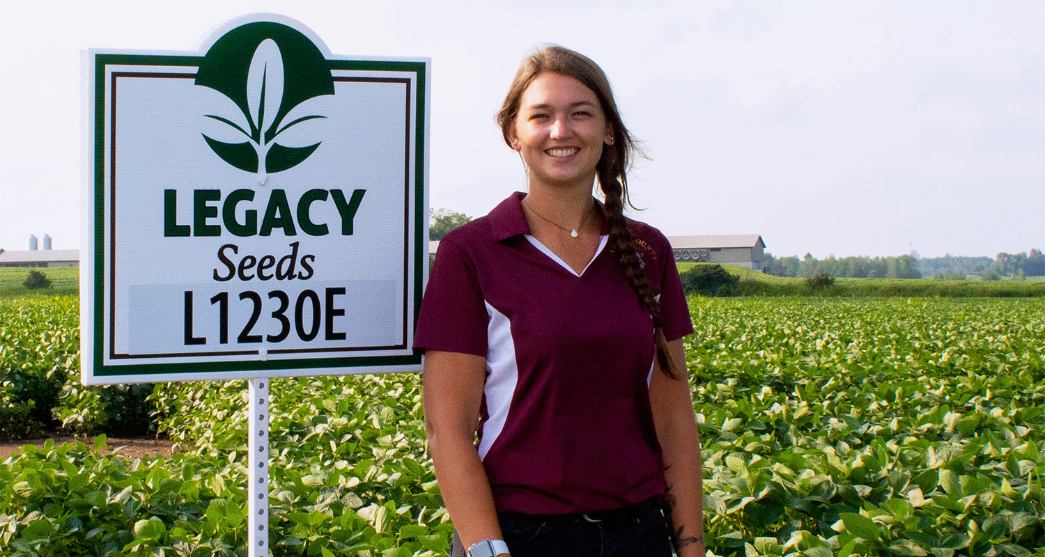 Katerina Kolzow poses in front of a farming field during her internship