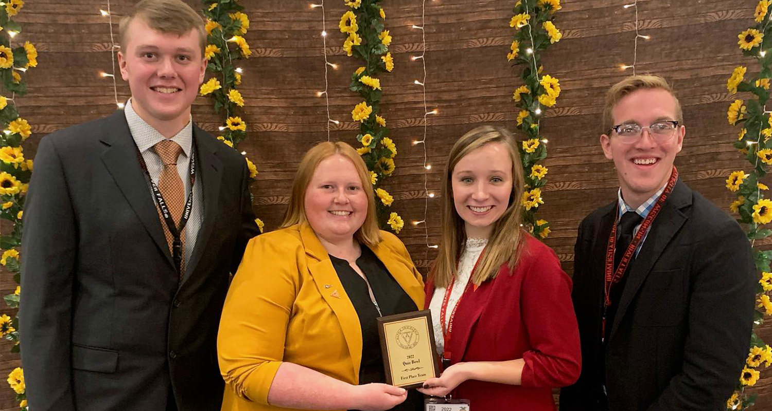 Four members of Alpha Tau Alpha stand with their Quiz Bowl award