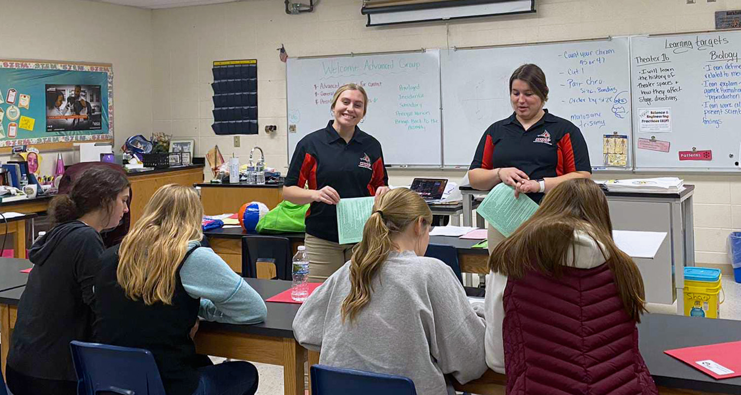 A group of students listen to two other AES society members speak in a classroom