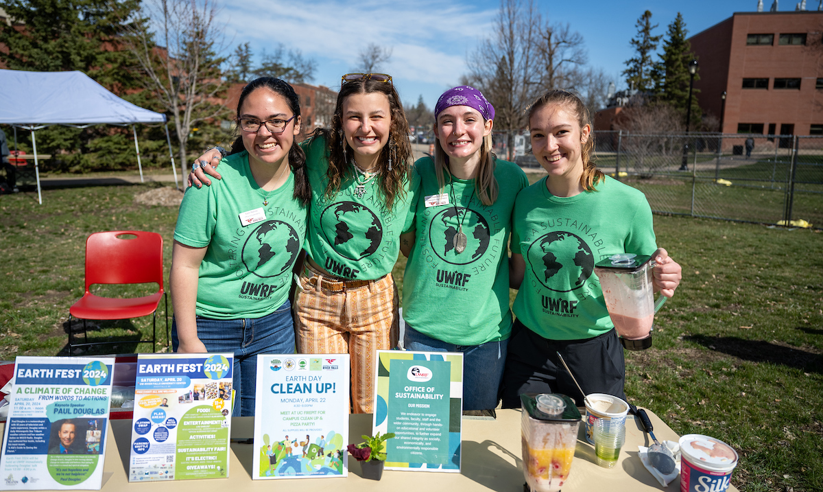 Students pose at a table wearing sustainability shirts and sharing materials