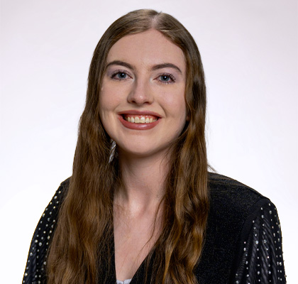 Headshot of Aine Crimmins, a female student with long brown hair wearing a black blouse