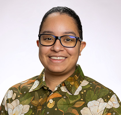 Headshot of Alexis Sanchez, a woman with black hair, black glasses and a patterned green and white button down shirt