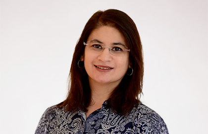 Headshot of Amber Qureshi, a woman with straight black hair and a blue patterned blouse