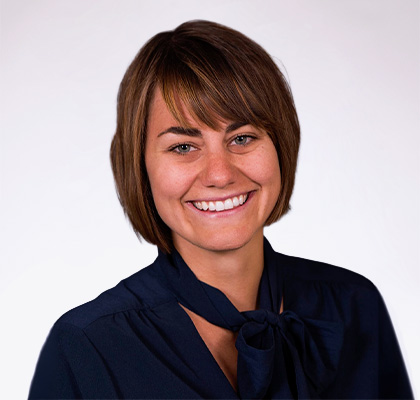 Headshot of Anna Schick, a young woman with short brown hair wearing a dark blue blouse