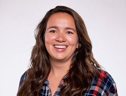 Headshot of Annemarie Schwery. A woman with long brown hair and a blue and red plaid button up