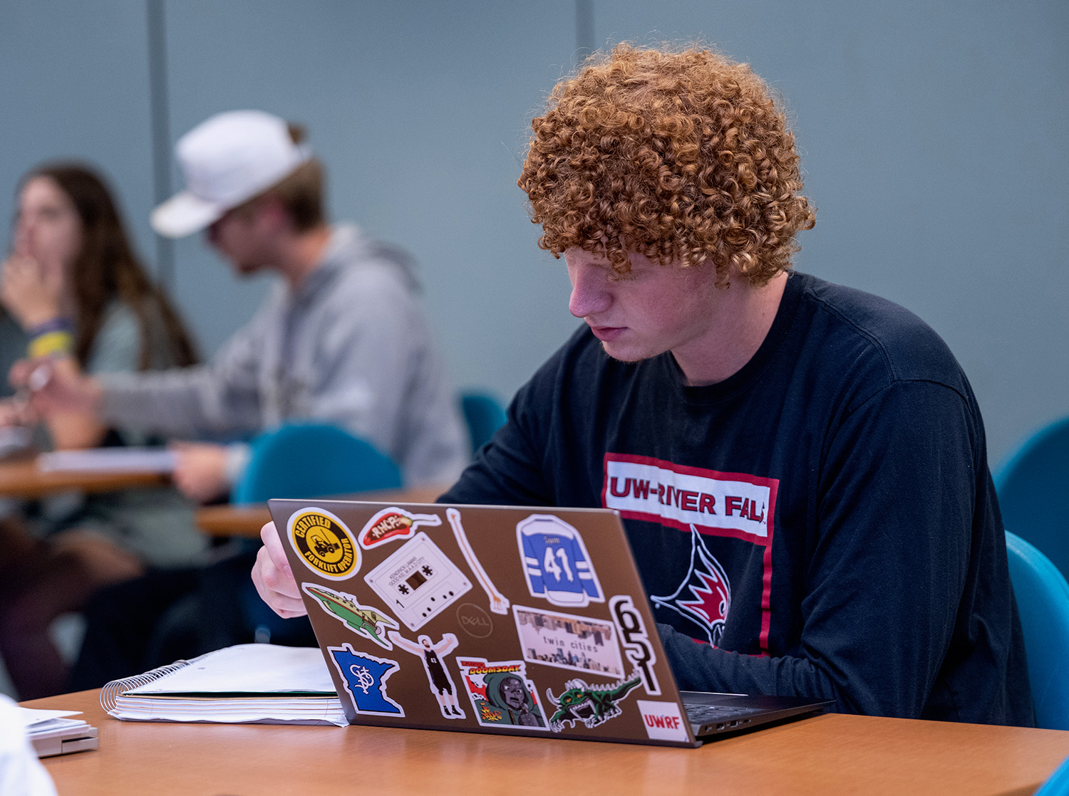 A male student works on his laptop during class