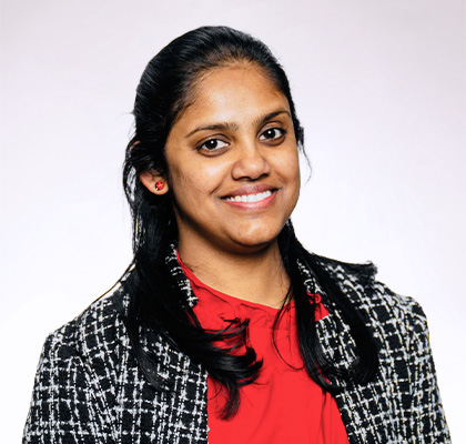 Headshot of Ashani Thilakarathne, a young Indian woman with long black hair wearing a black and white blazer over a red blouse