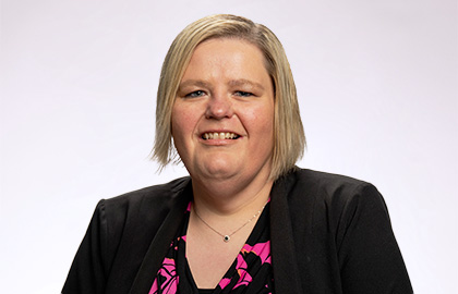 Headshot of Becky Pribnow, a woman with short blonde hair wearing a pink blouse and black blazer