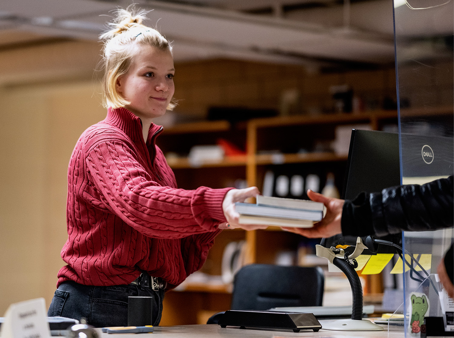 A student hands a stack of books to the circulation staff member