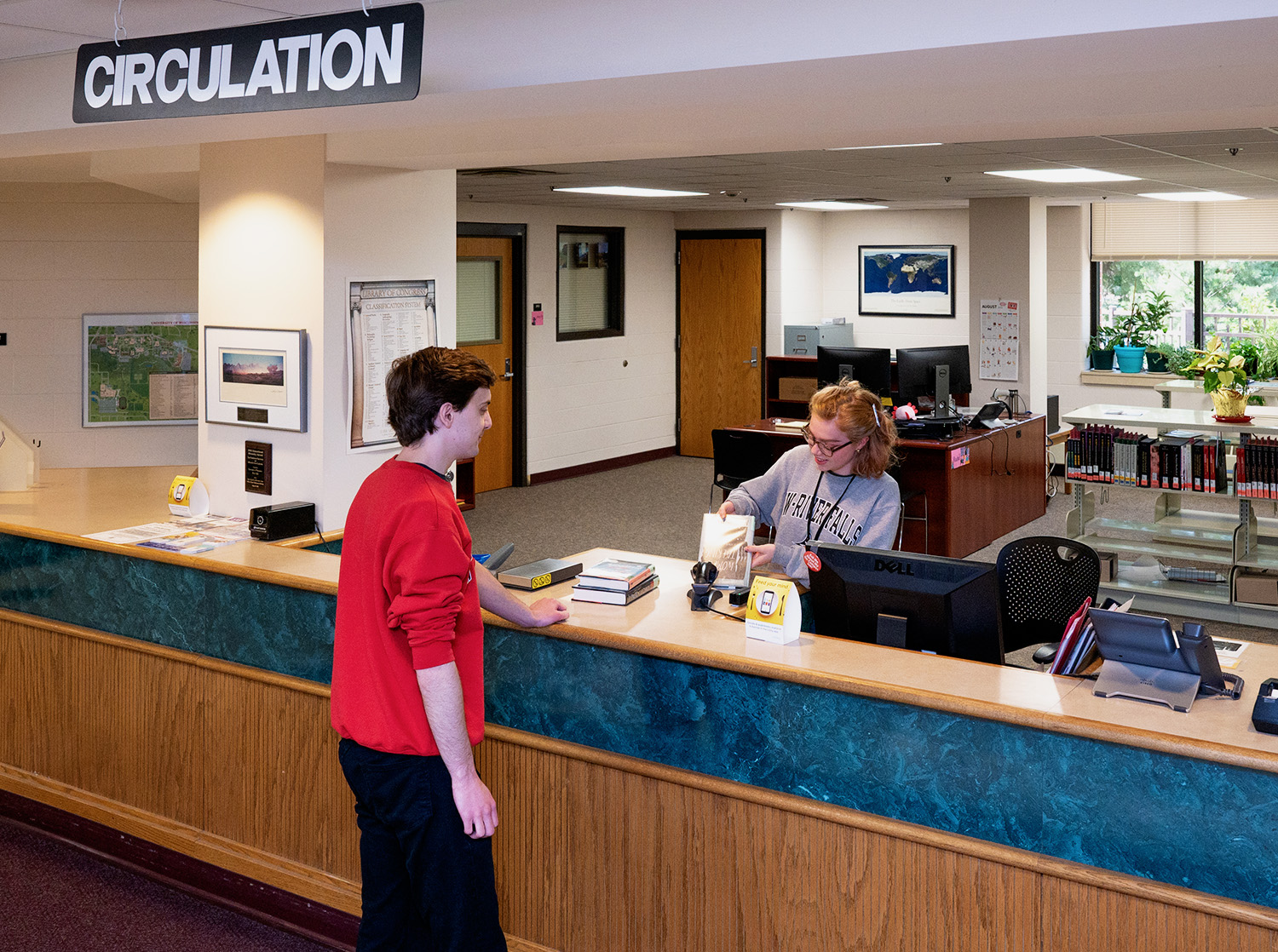 A student worker checks out books at the circulation desk