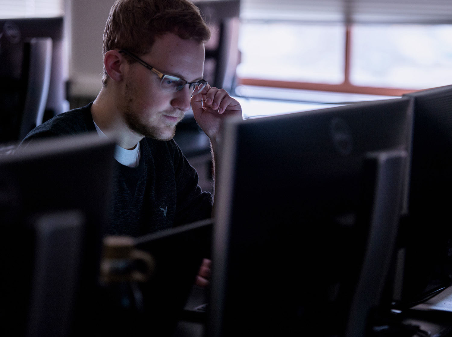A male students face is lit up by the glow of a computer screen