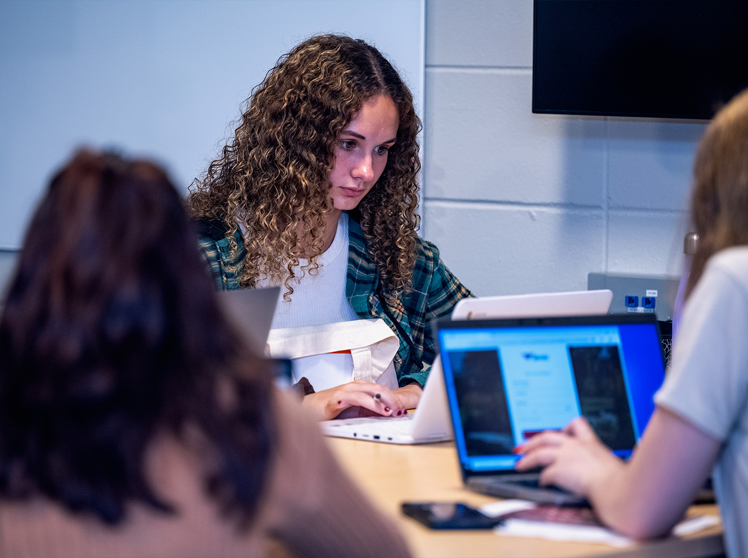 A group of students at a table working on their laptops