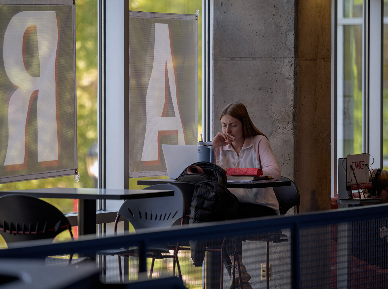 A female student sits at a table with their laptop in the University Center.