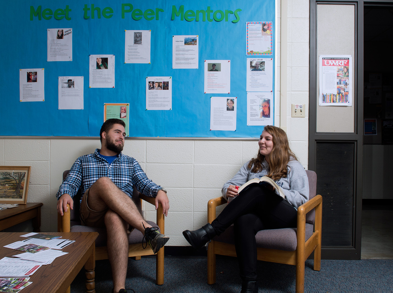 A male and female student sit in two chairs opposite each other talking