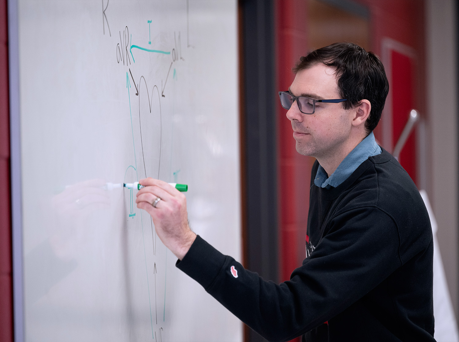 A professor writes on a whiteboard