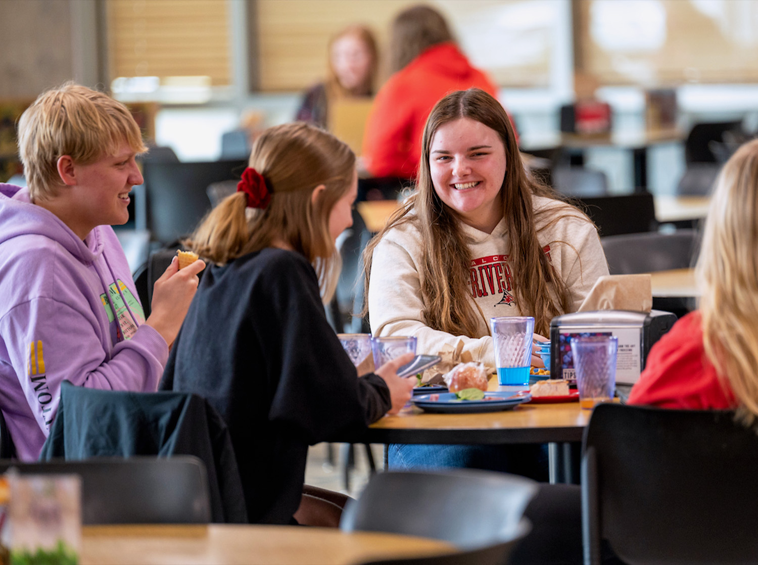 A small group of students sit in a booth in the Riverside Commons