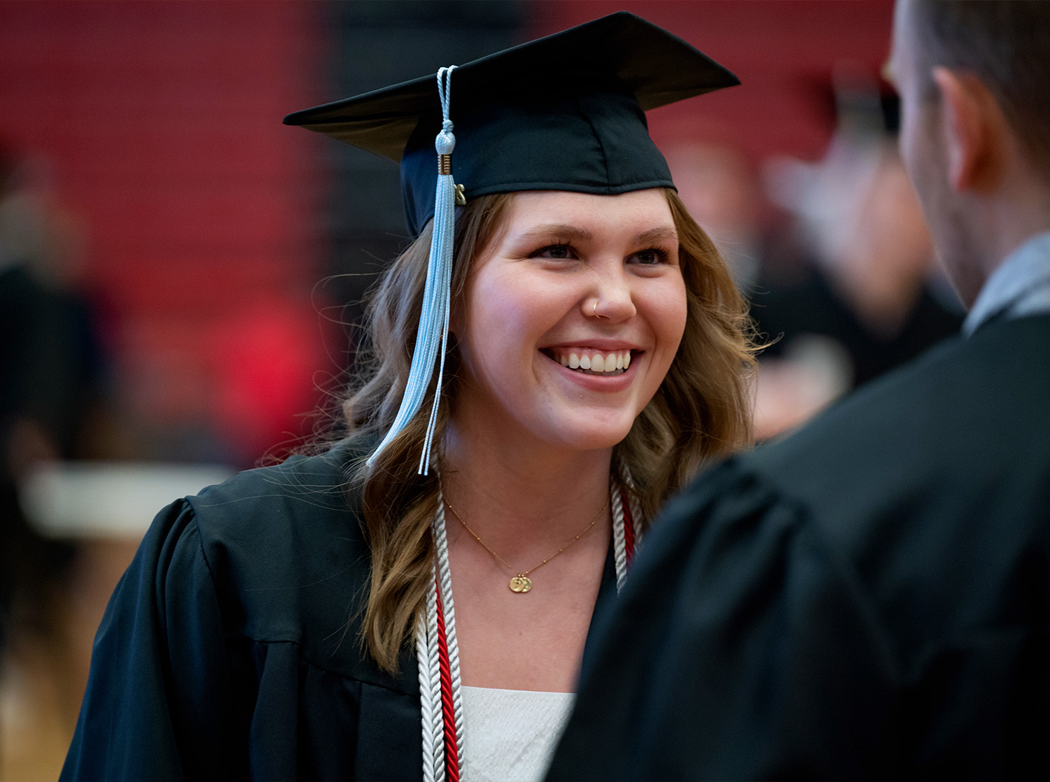 A female student wears a cap and gown during their commencement ceremony