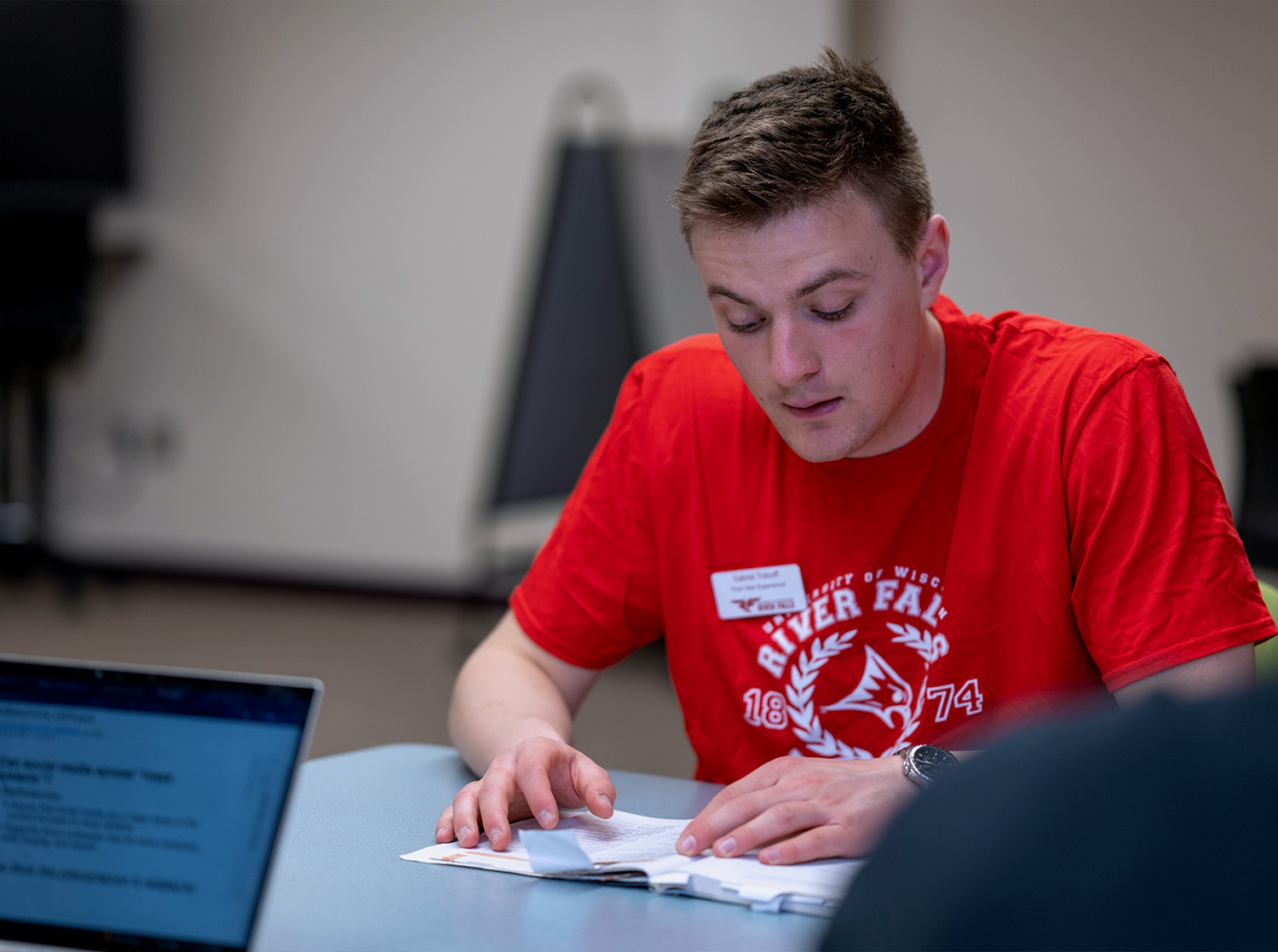 A male student reviews documents on a table in front of him