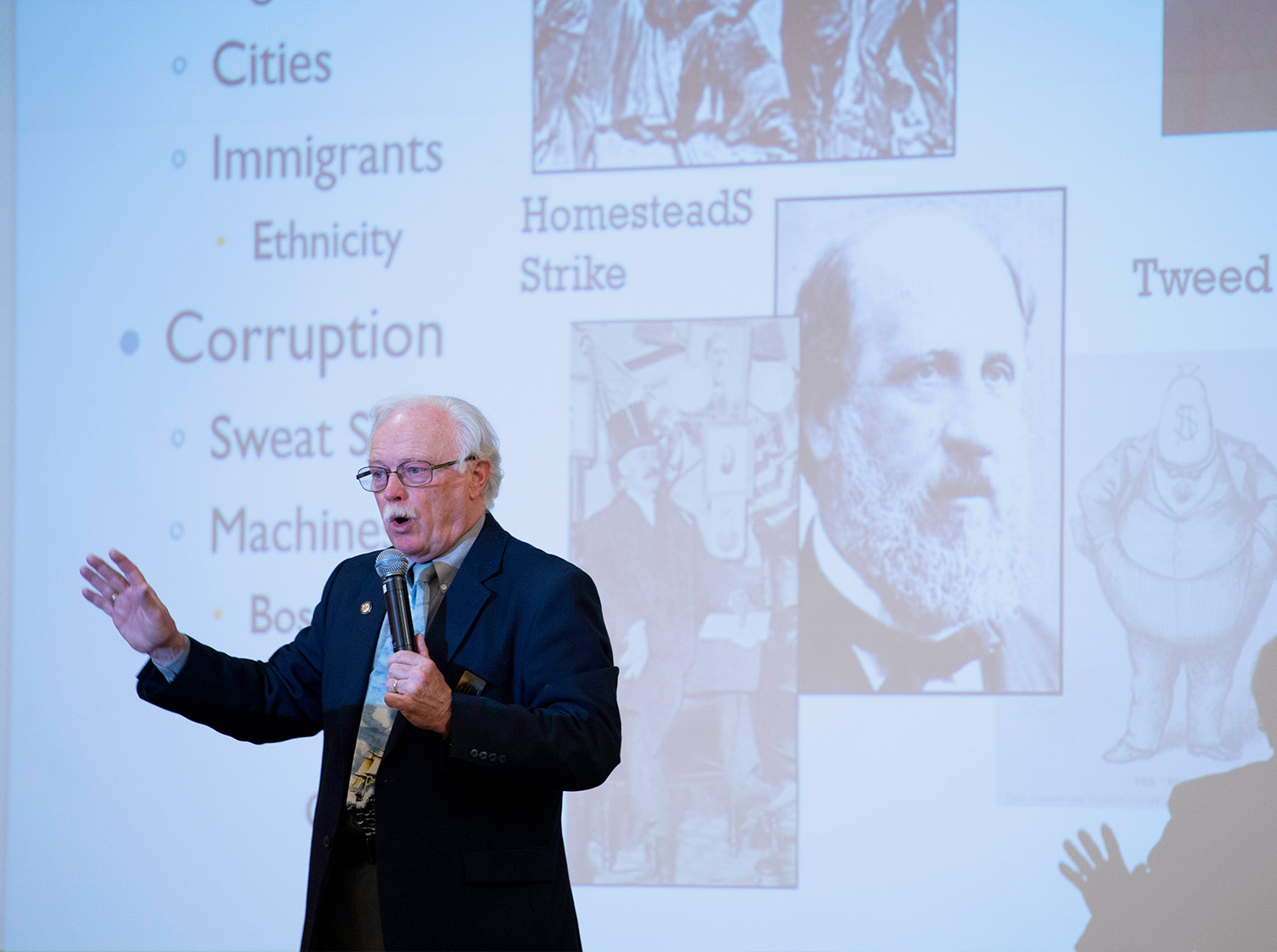 A male history professor hold a microphone during a lecture