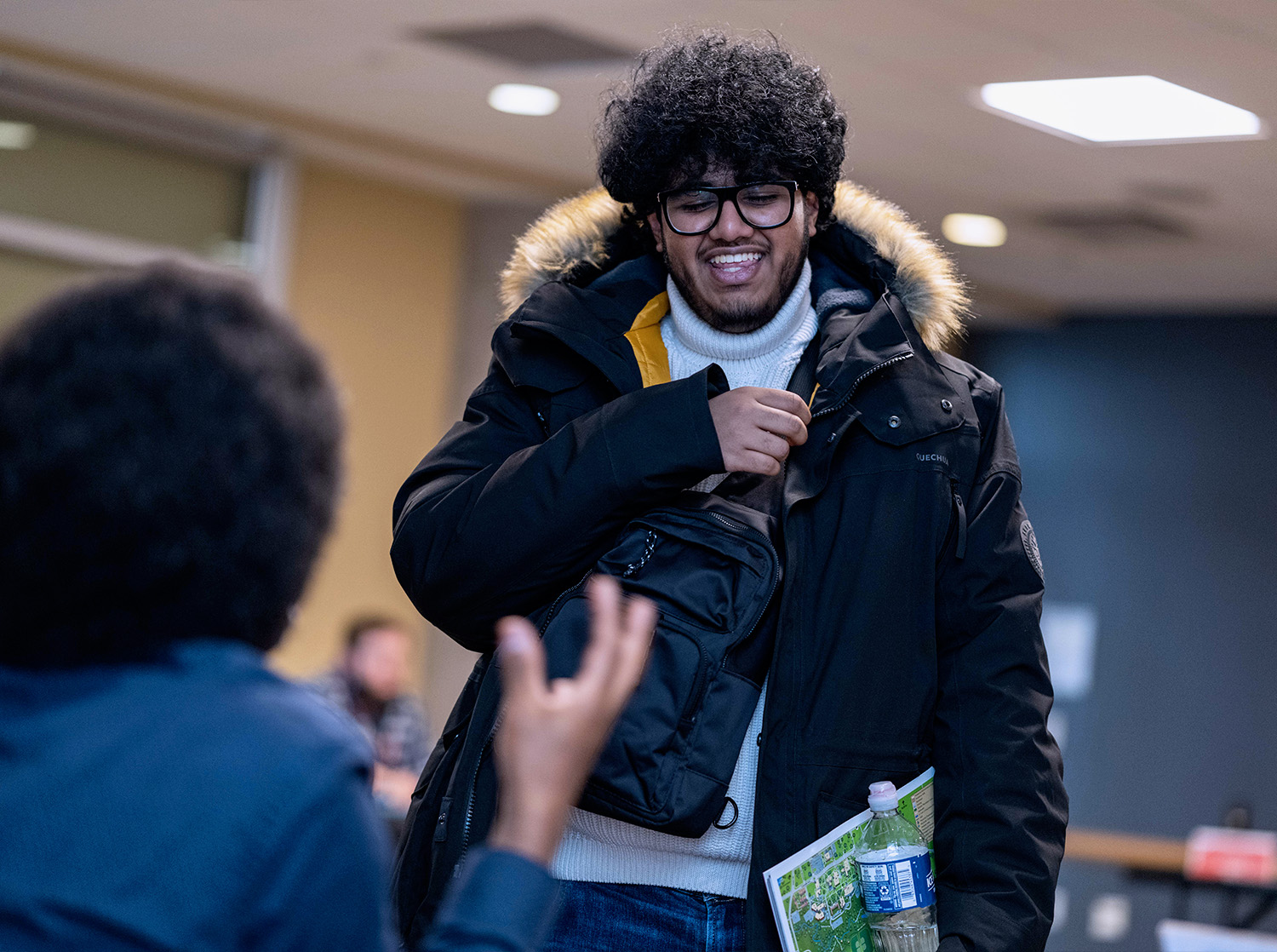 A male student talks to another student behind a table at orientation