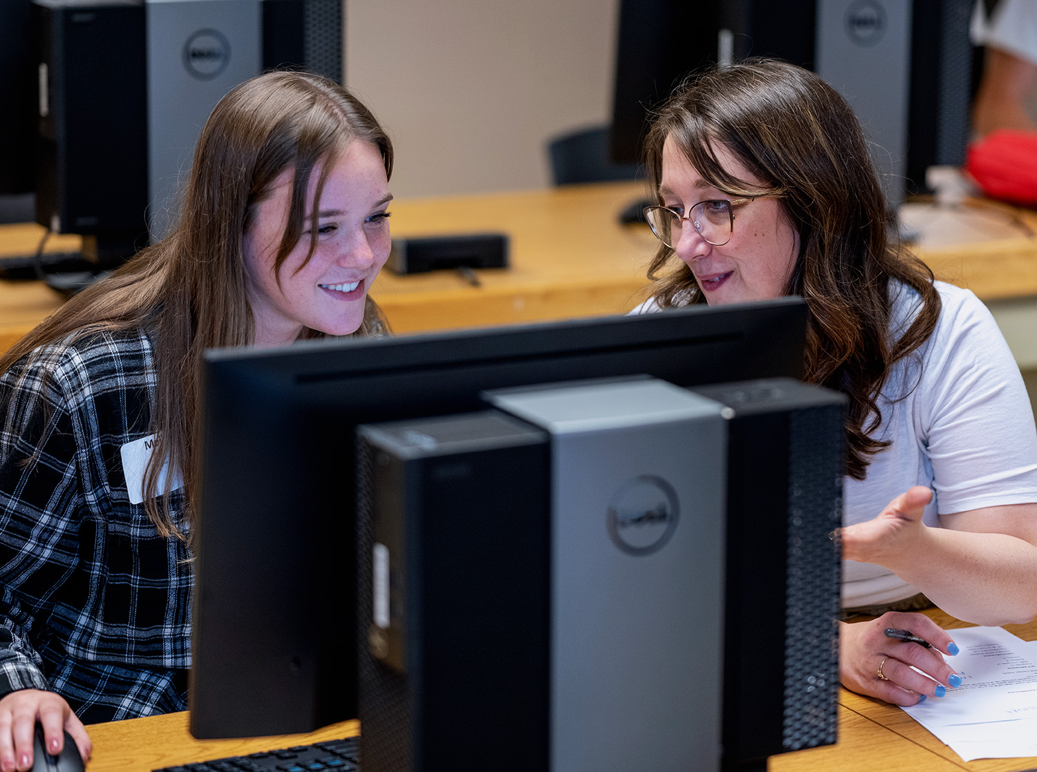 A library staff member helps a student find something on their computer