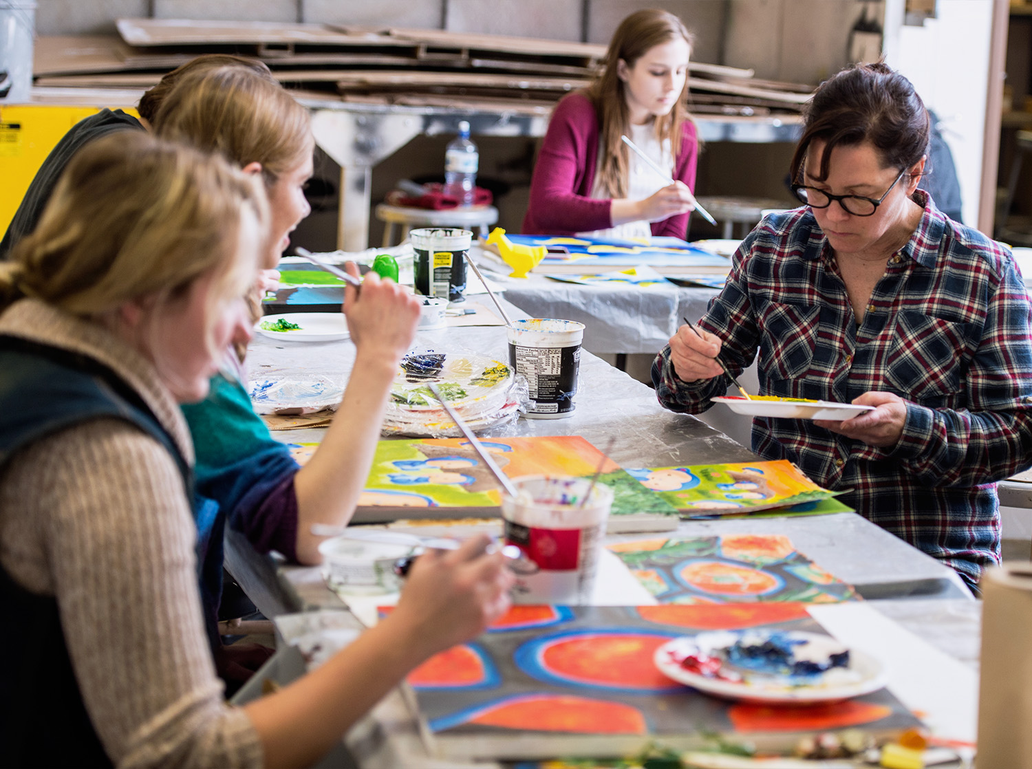 Students paint on canvas during an art class