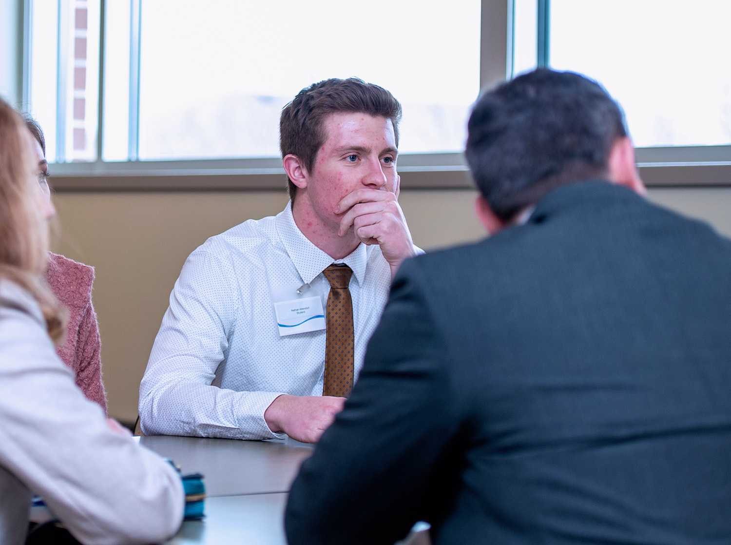 A male student listens to another person as they sit at a table during the Innovation Challenge
