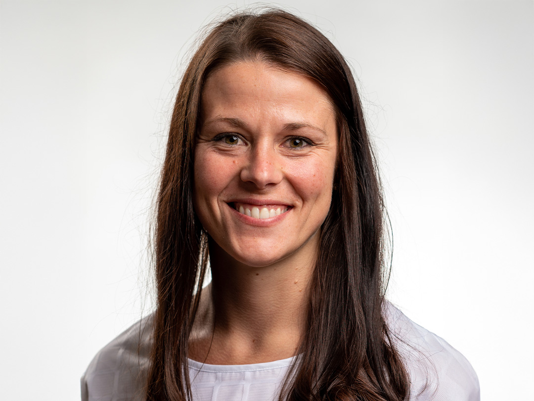 Headshot of Brooke Krejci, a young woman with long brown hair wearing a white t-shirt