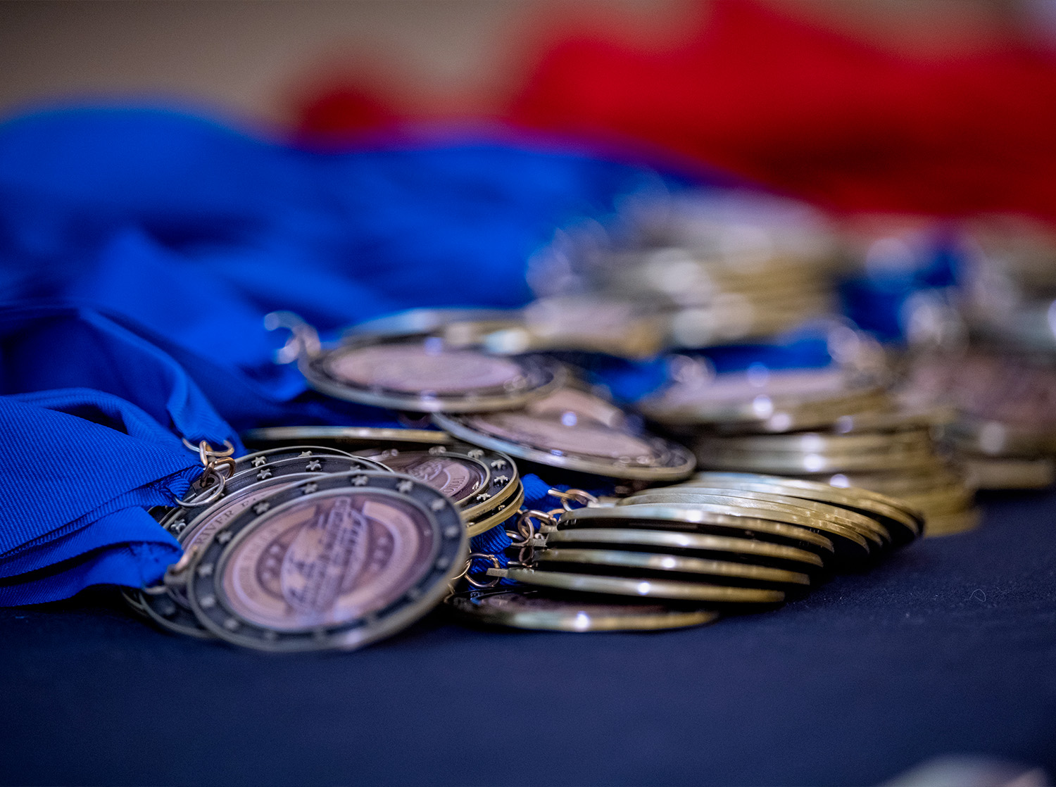 A stack of medals with blue ribbons sit on a table