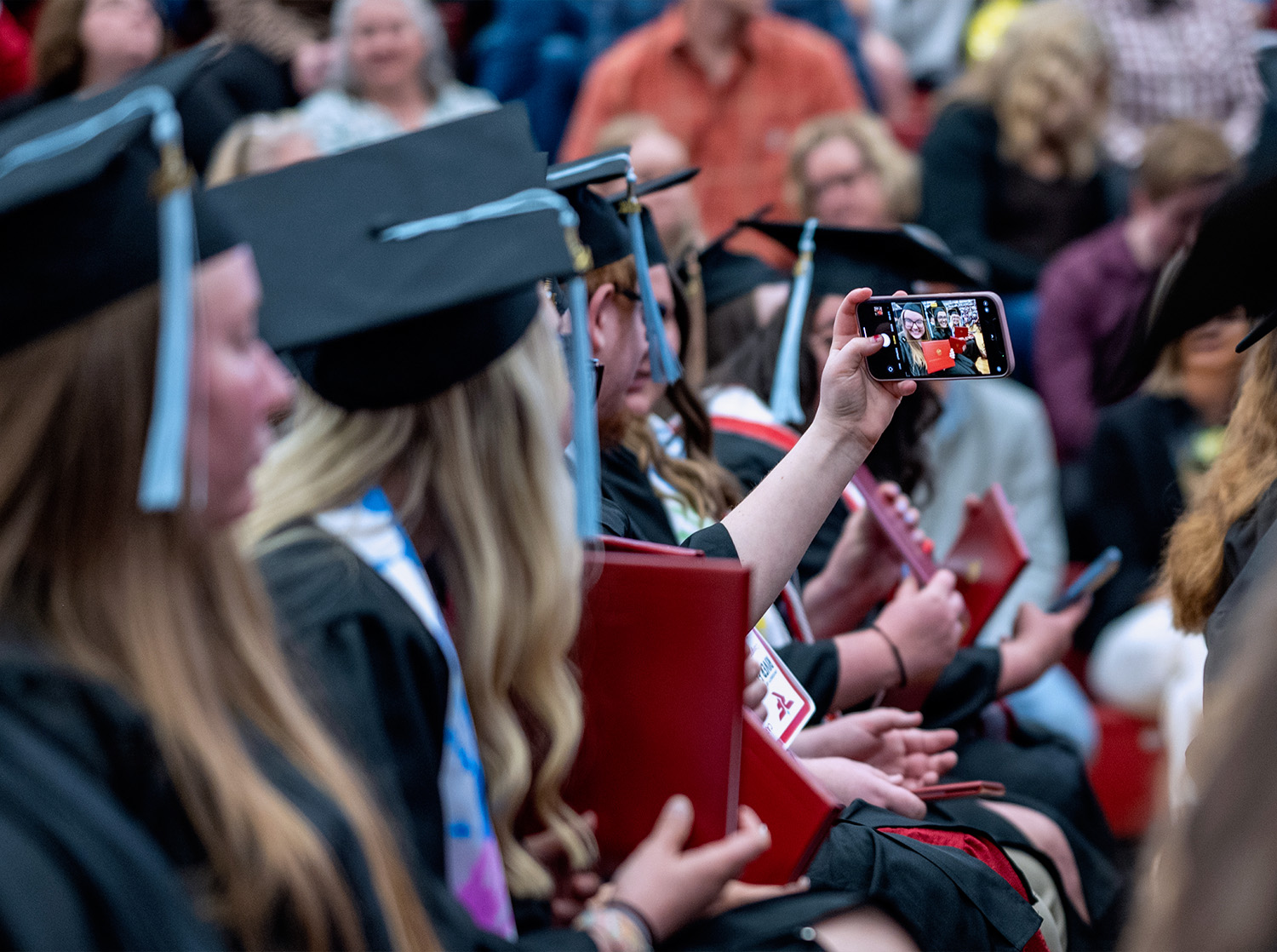 Graduates take a selfie while they attend commencement