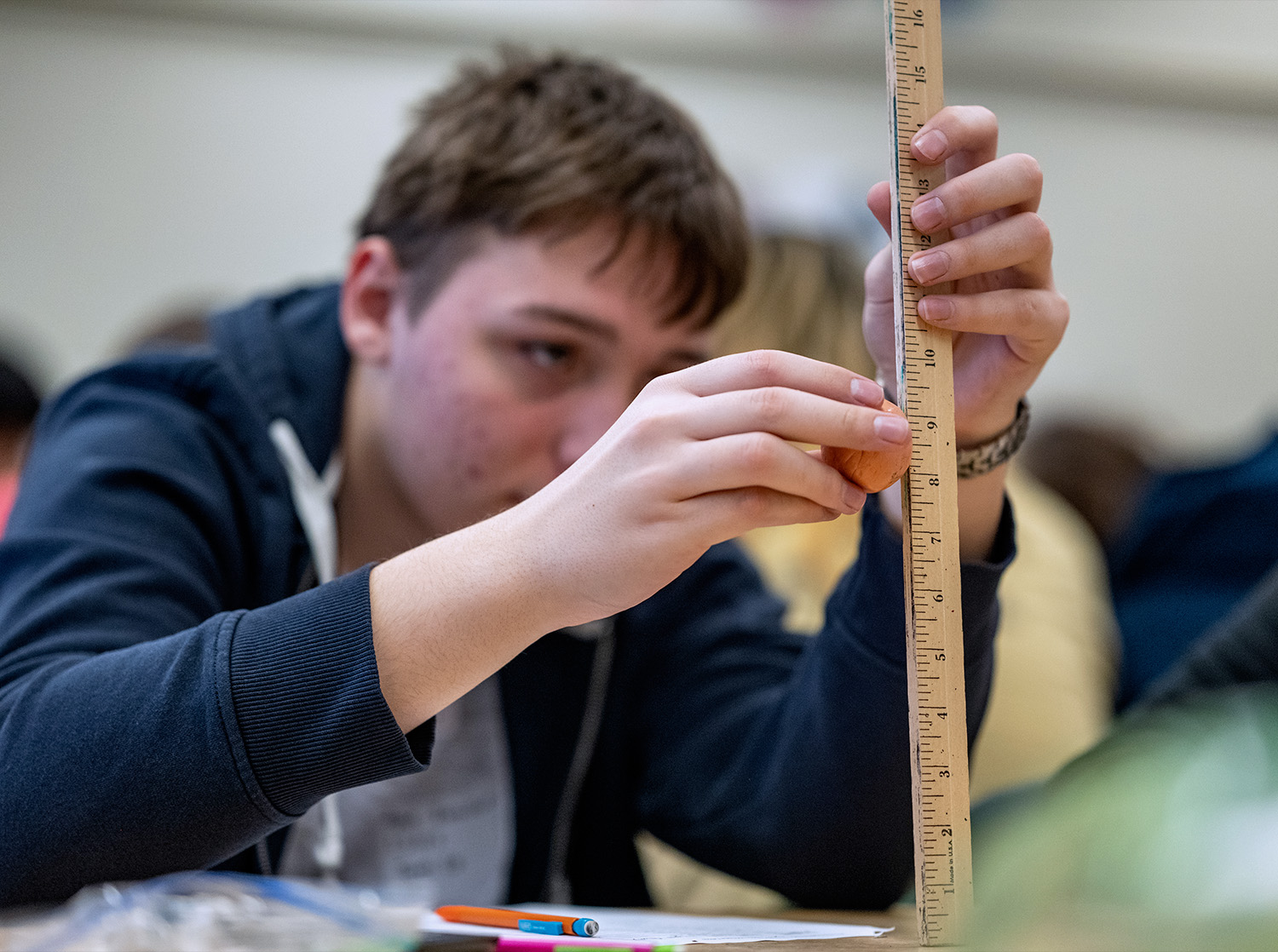 A person uses a measuring stick to take the height measurement