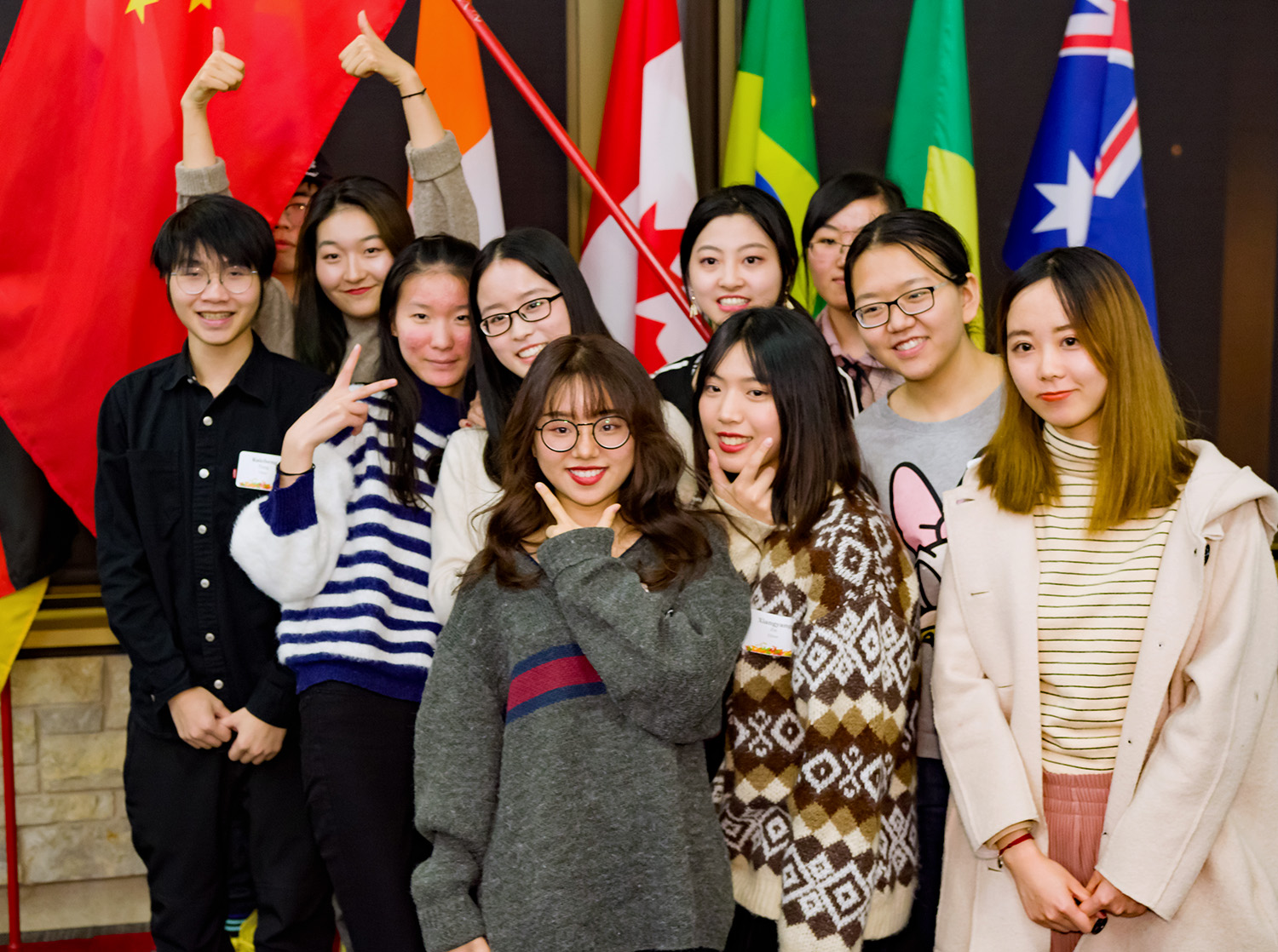 A group of international students pose in front of country flags