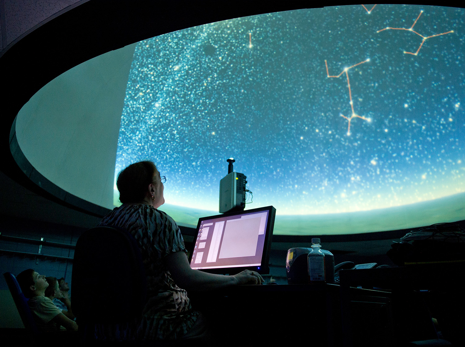 A professor looks up at the ceiling in the planetarium