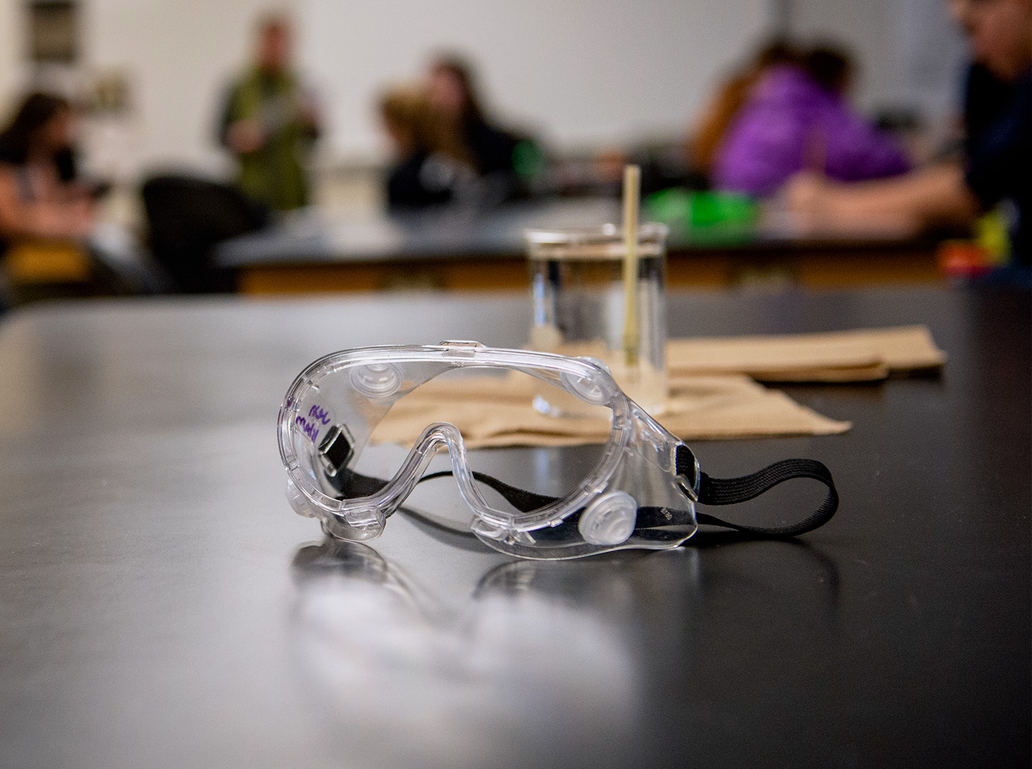 A pair of safety goggles sit on a lab table in a physics lab