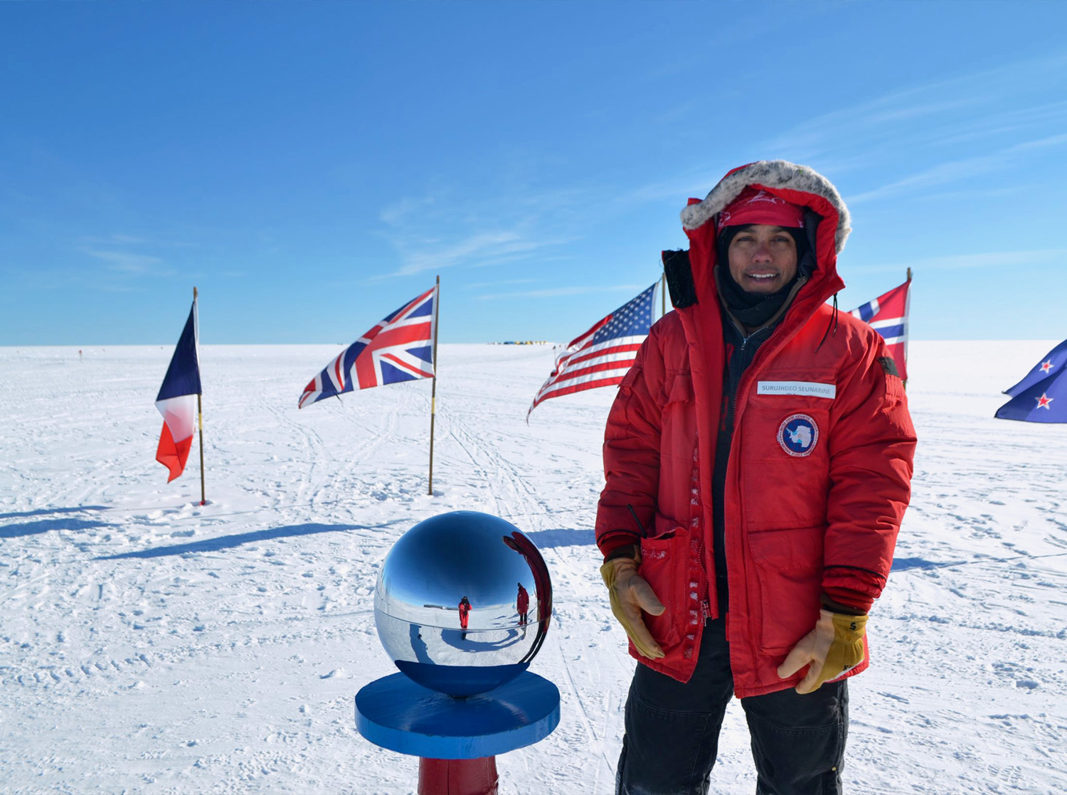 A professor stands in cold weather gear at the South Pole