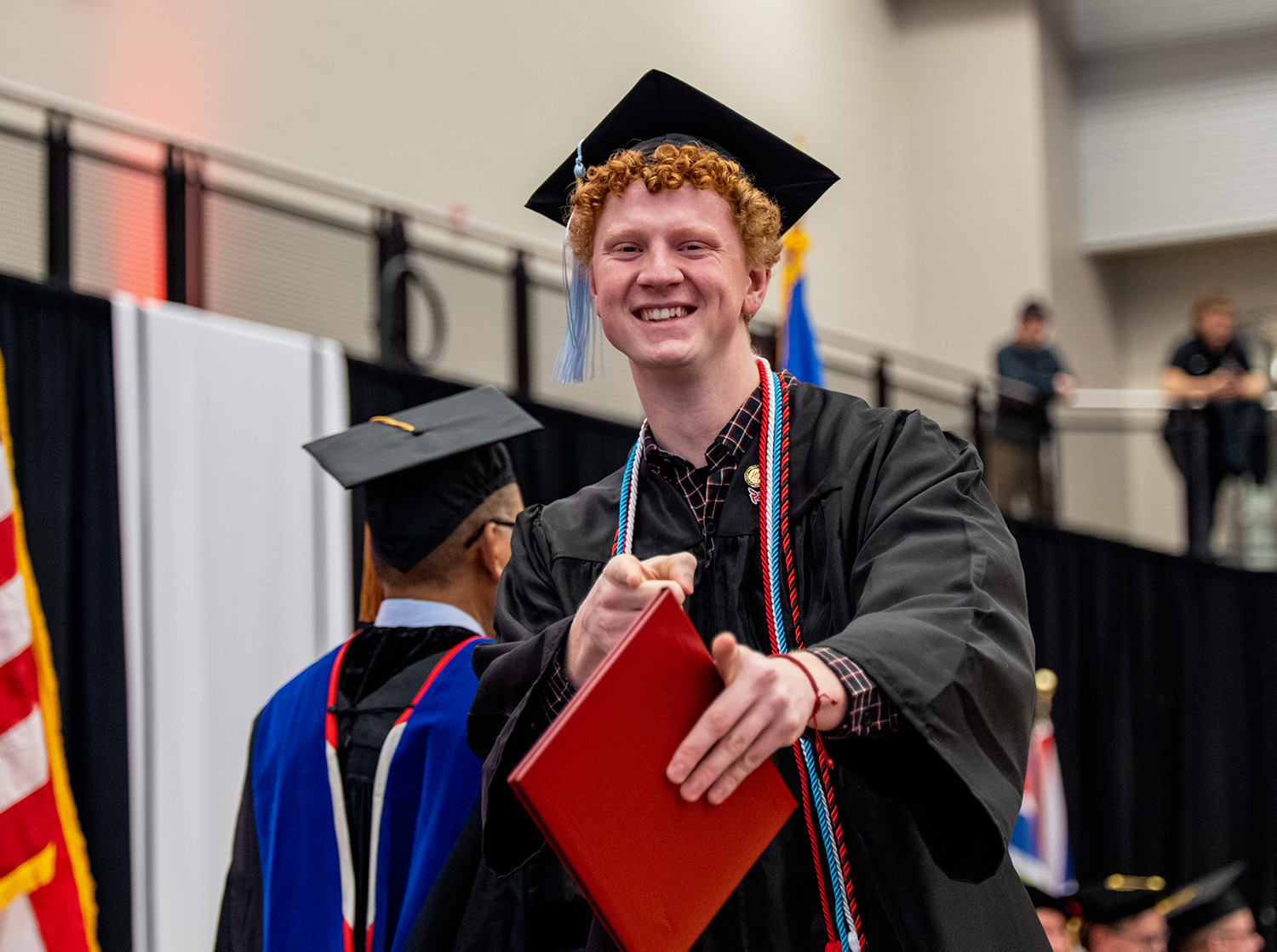 A student at graduation posing for the camera after crossing the stage and earning their degree