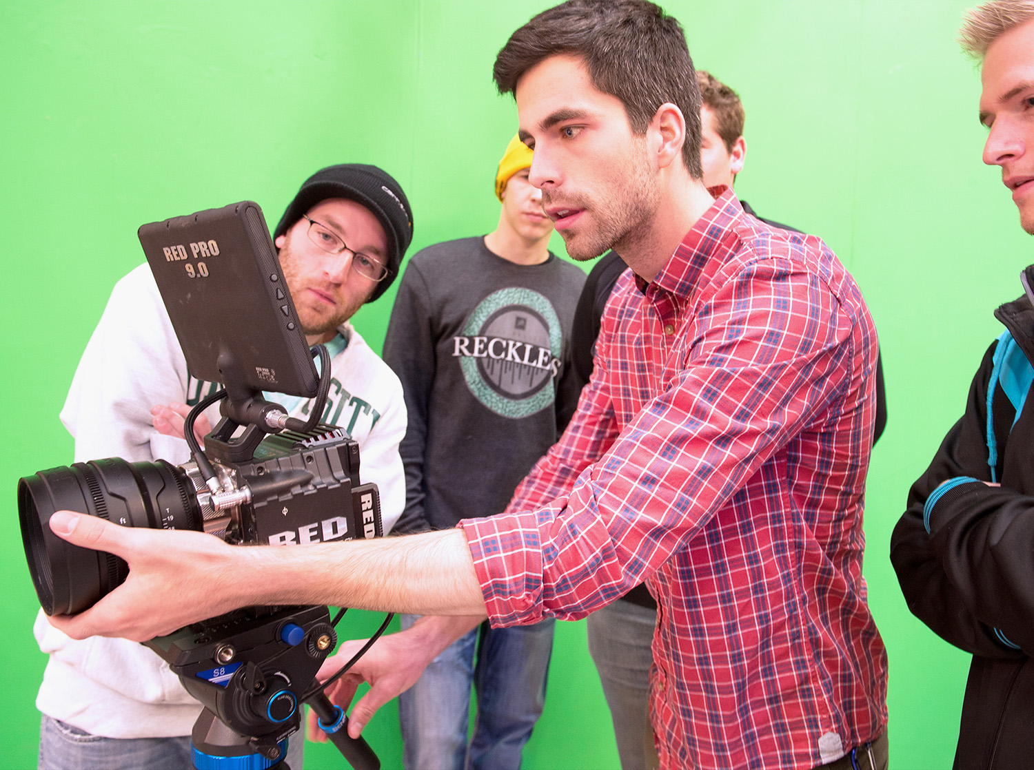 A group of students configure a video camera in front of a green screen
