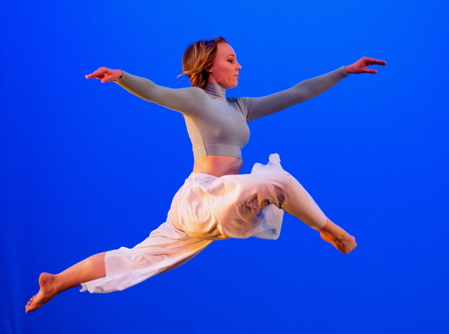 A female student leaps through the air during a dance performance