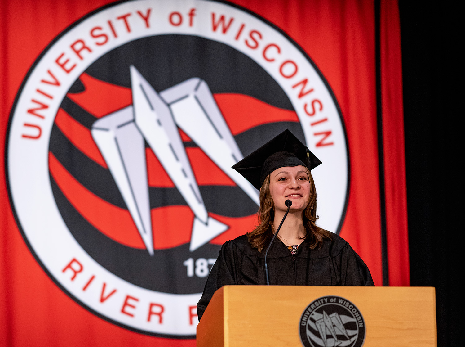 A female speaker stands at a podium during commencement.