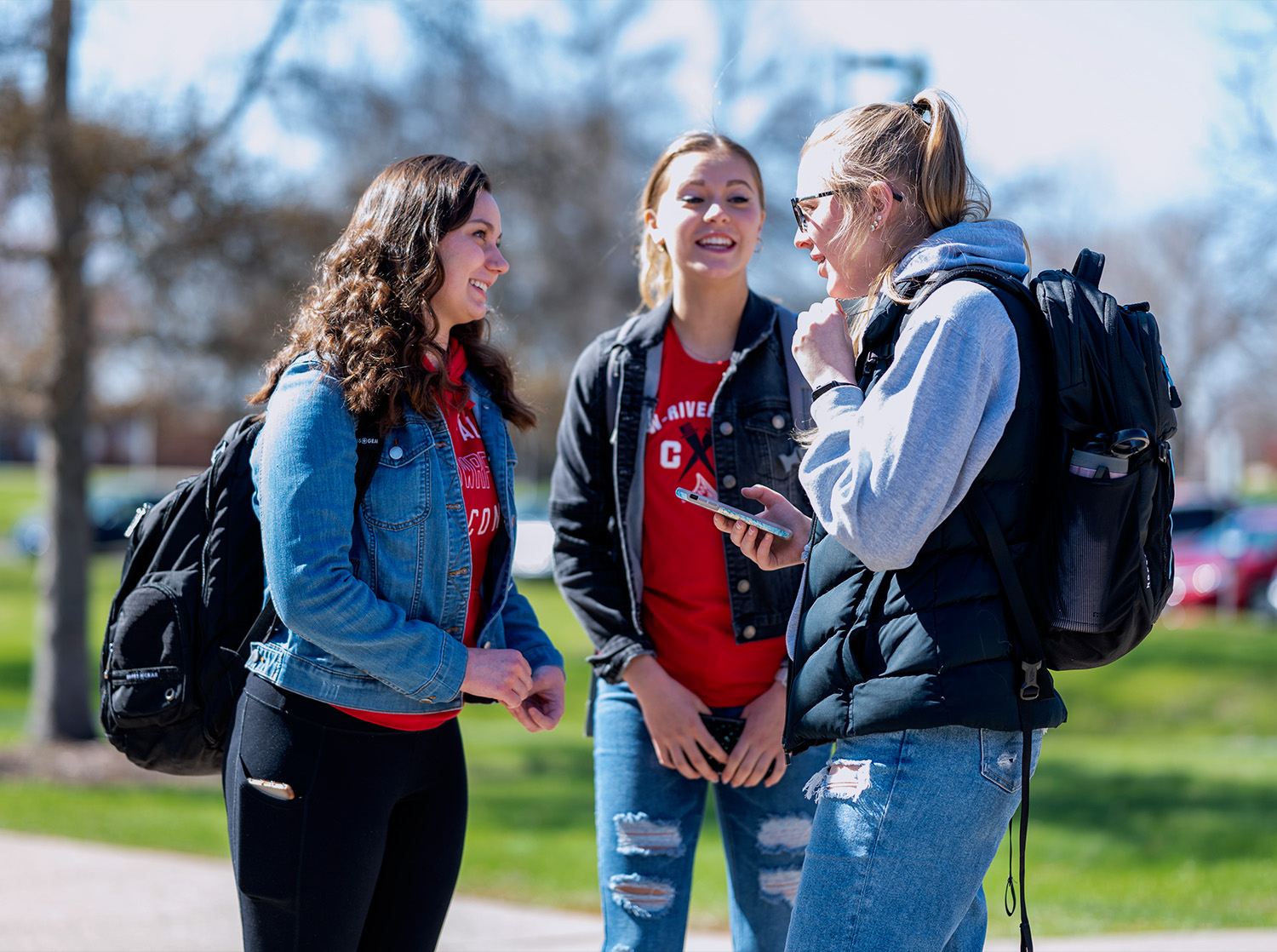 Three female students talk outside on the campus mall