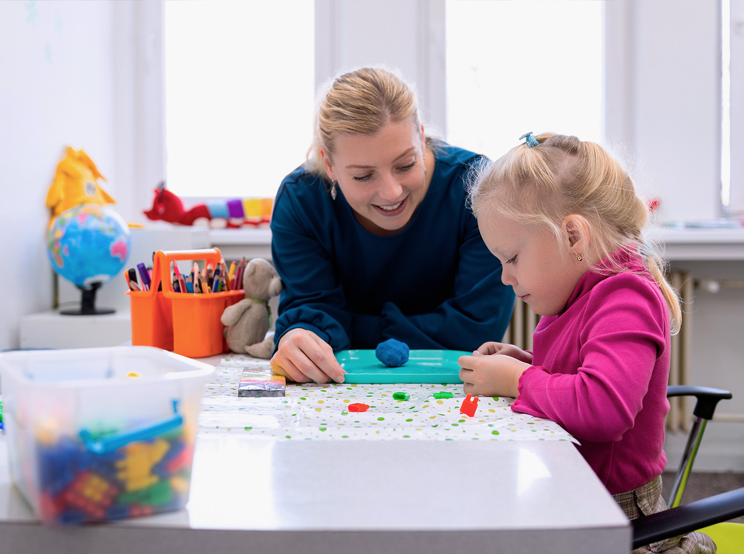 A school psychology graduate student speaks to a young child in a classroom