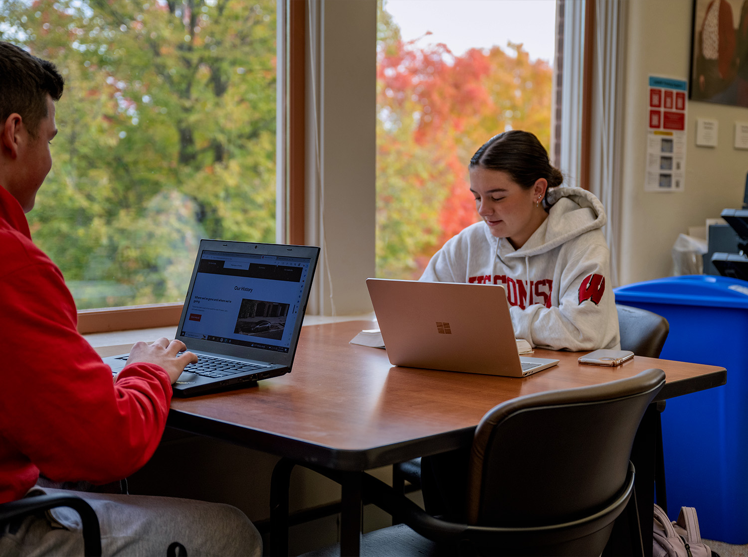 Two students sit at a table working on a project together