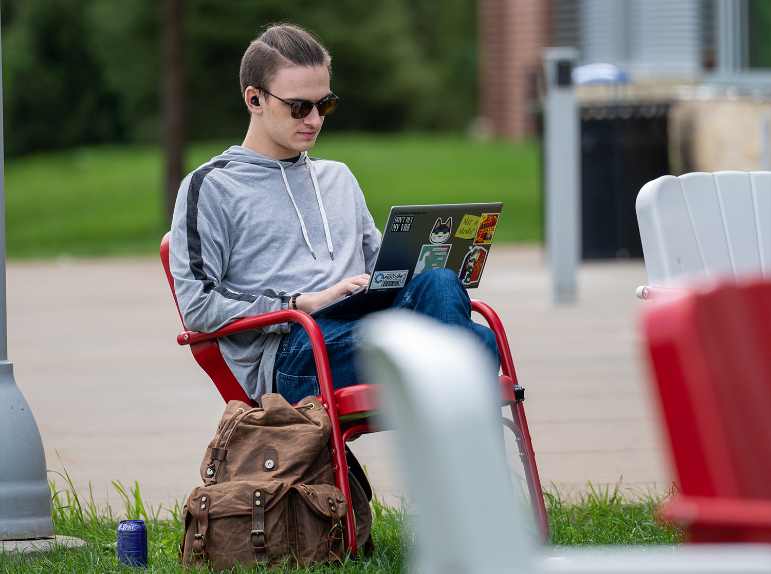 A male student sits outside the University Center doing homework on their laptop