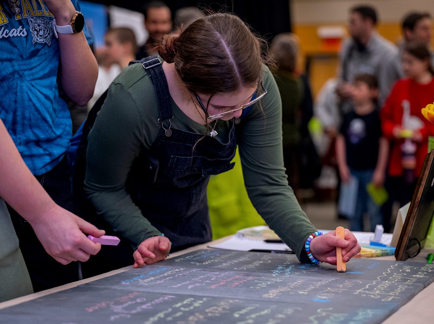 A woman writes on a blackboard with orange chalk during Earth Fest 2024