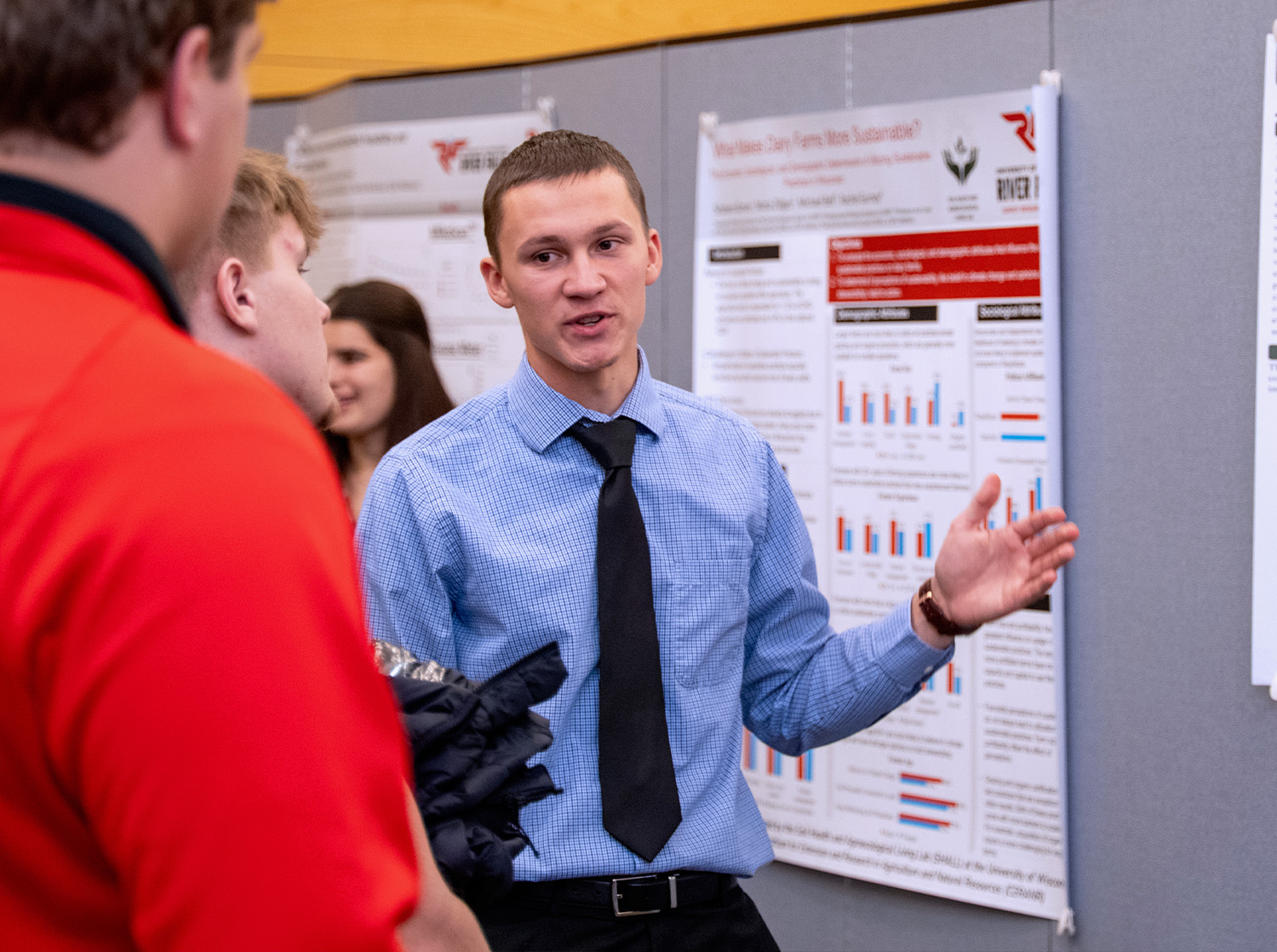 A male student presents his research poster to community members during the URSCA Fall Gala