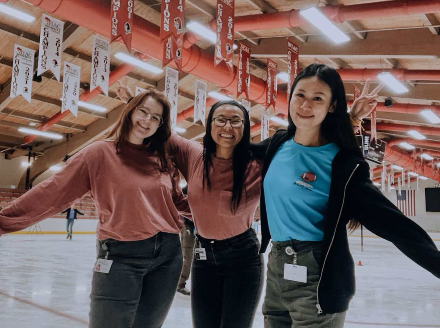 Three female students pose while ice skating in Hunt Arena