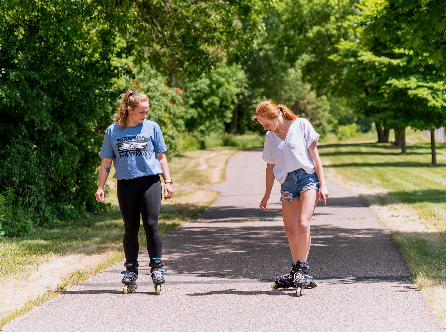 Two students rollerblade on Bluestem Path on campus