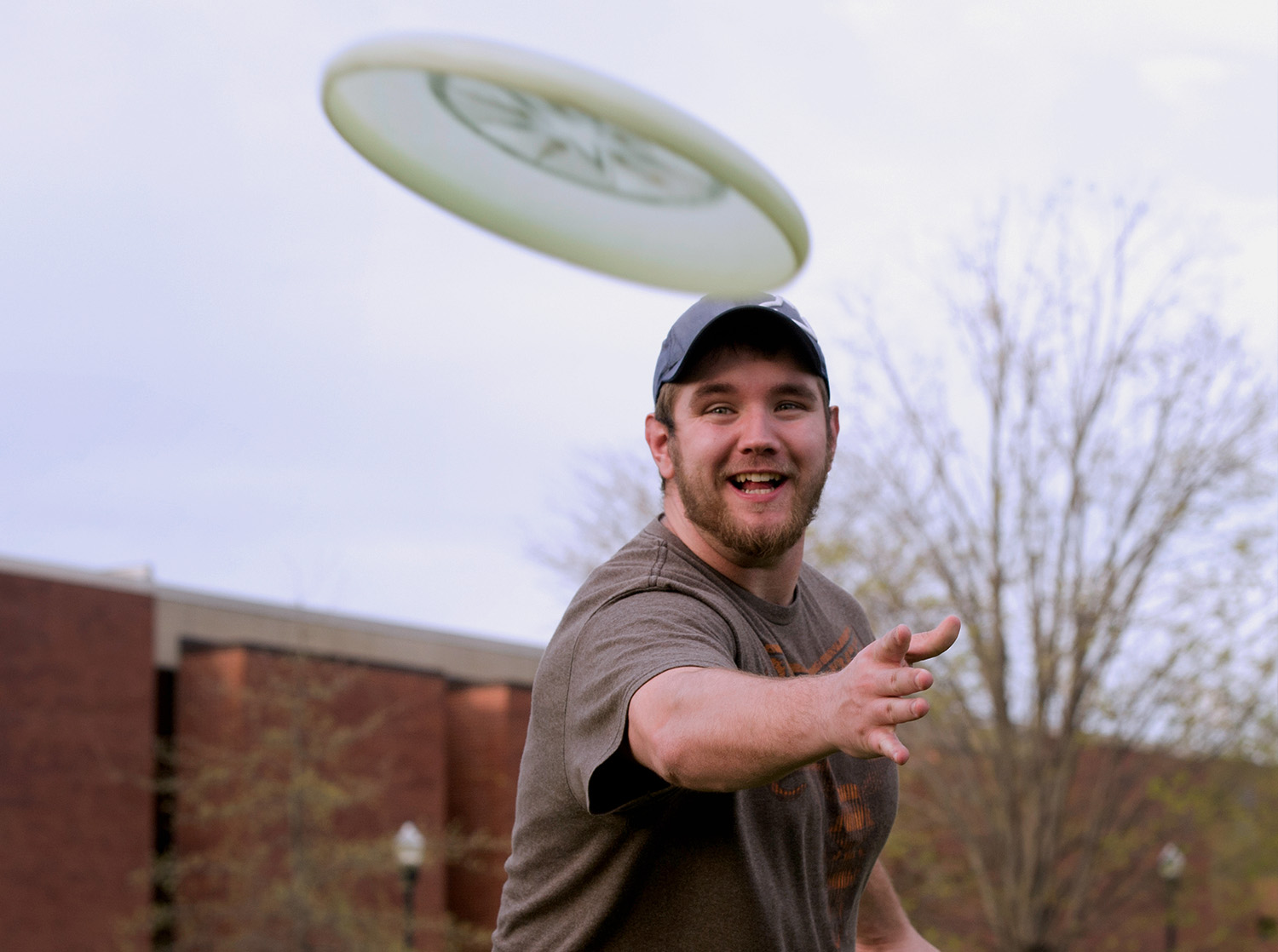 A student throws a frisbee to a friend on the campus mall