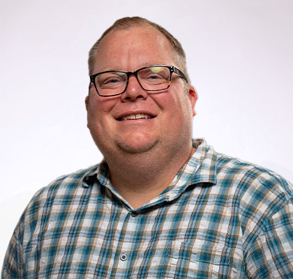 Headshot of Chris Holtkamp, a man wearing glasses and a green plaid button down shirt 